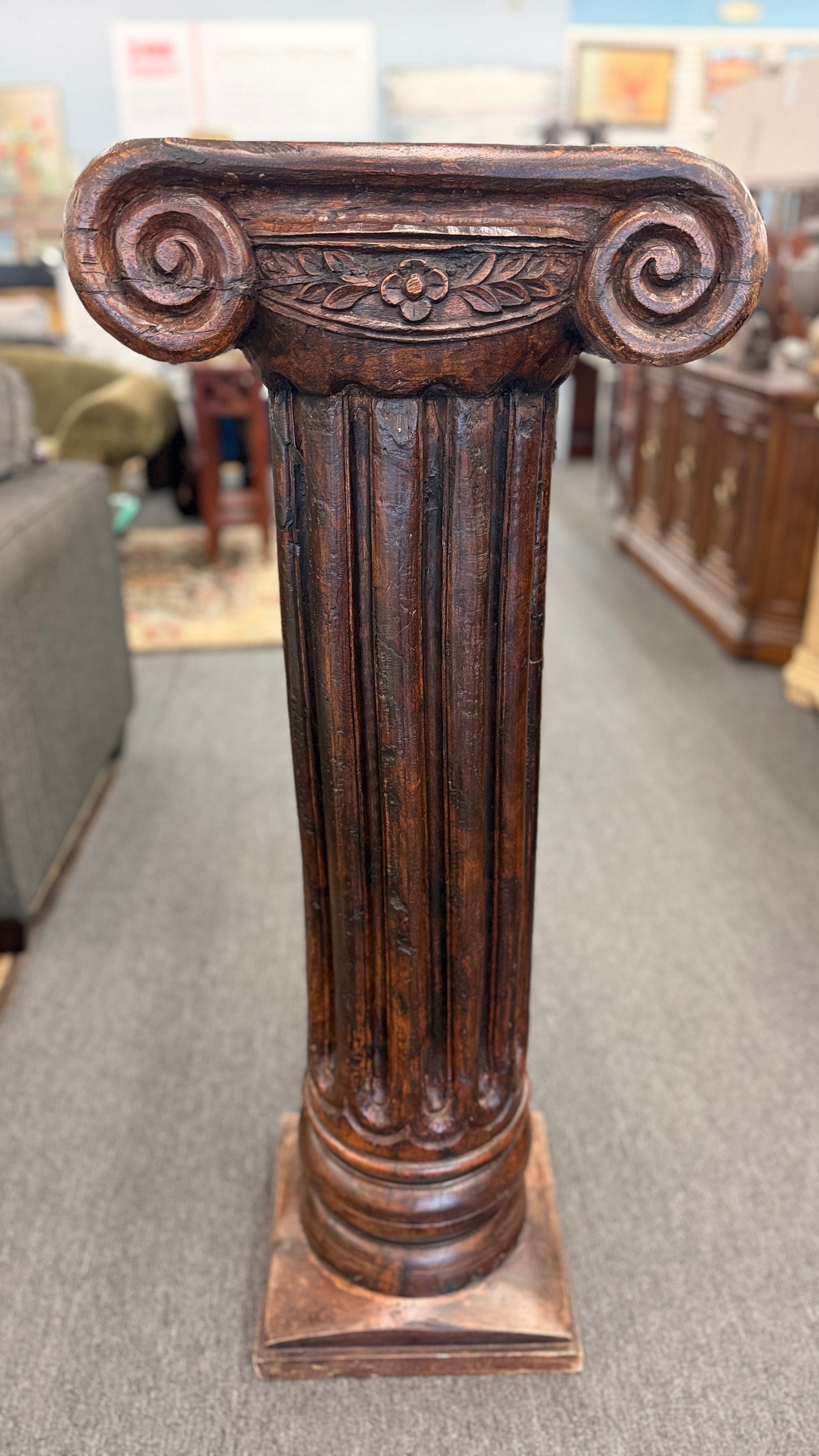 A classical wooden architectural pedestal featuring a carved Ionic scroll capital with floral motifs, a fluted shaft, and a square plinth base in excellent condition.