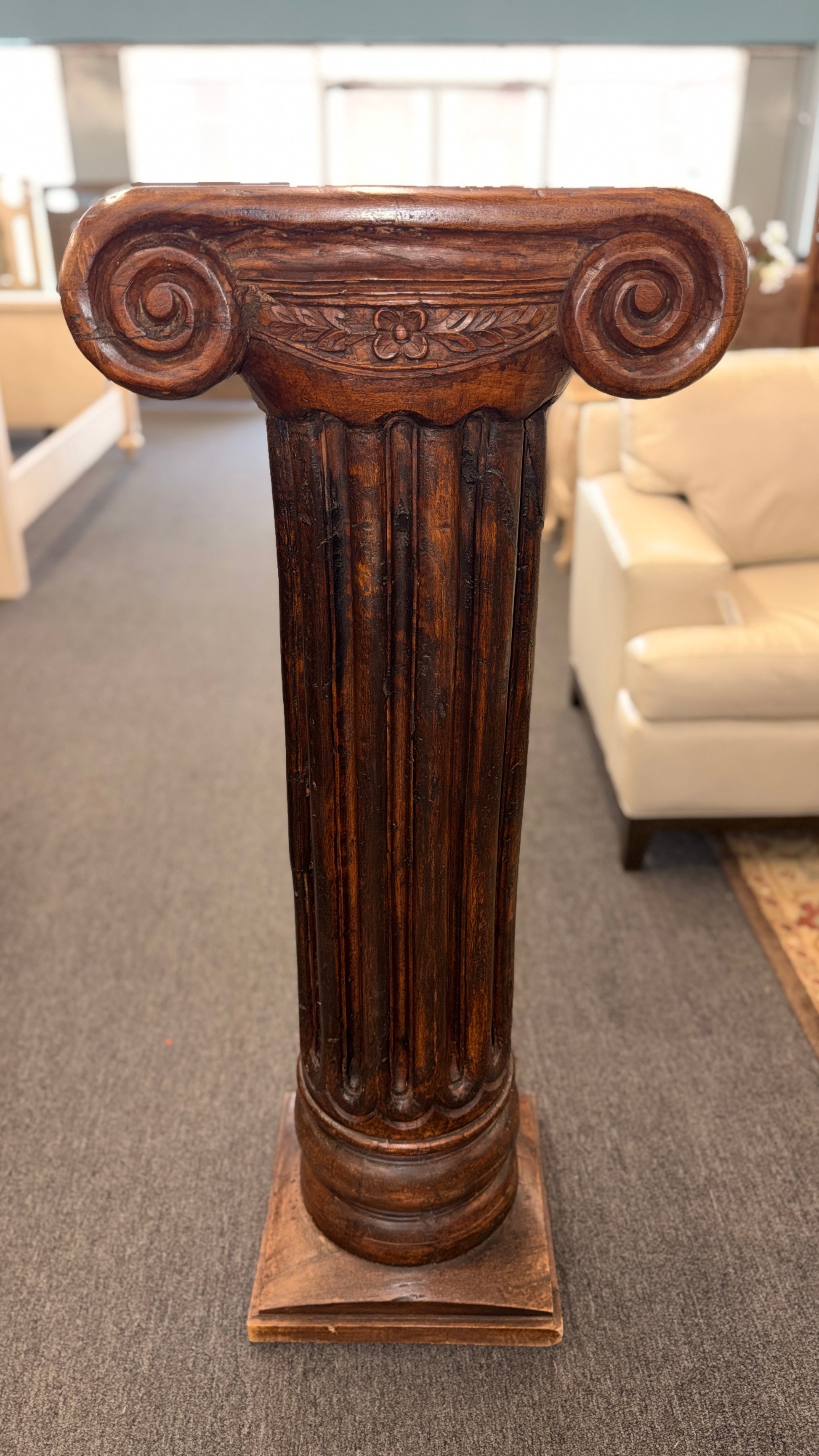A classical wooden architectural pedestal featuring a carved Ionic scroll capital with floral motifs, a fluted shaft, and a square plinth base in excellent condition.