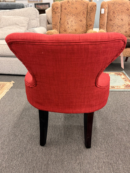 A contemporary accent armchair upholstered in textured burnt-orange fabric with button-tufted back detailing and dark-finished tapered legs in good condition.
