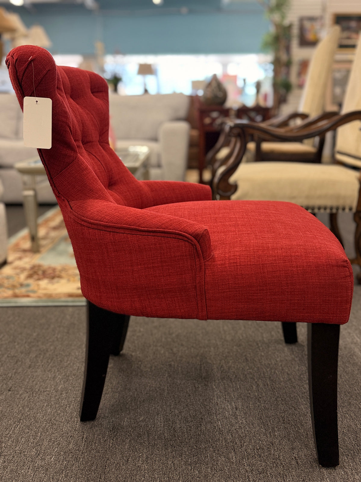 A contemporary accent armchair upholstered in textured burnt-orange fabric with button-tufted back detailing and dark-finished tapered legs in good condition.