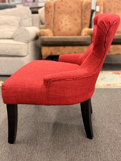 A contemporary accent armchair upholstered in textured burnt-orange fabric with button-tufted back detailing and dark-finished tapered legs in good condition.