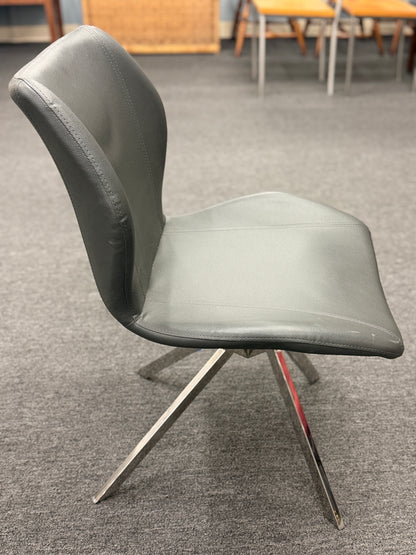 An accent office chair featuring sleek charcoal-gray faux leather upholstery with stitched seams, set on four angled chrome legs in good condition.