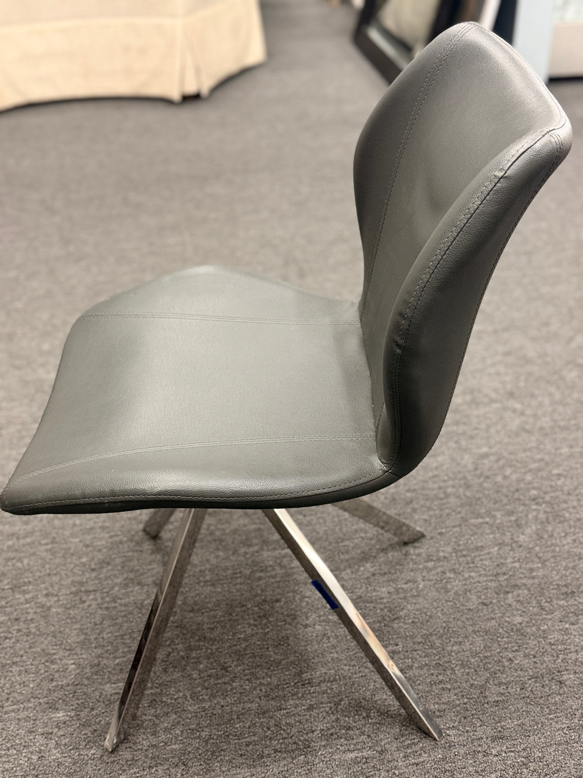 An accent office chair featuring sleek charcoal-gray faux leather upholstery with stitched seams, set on four angled chrome legs in good condition.