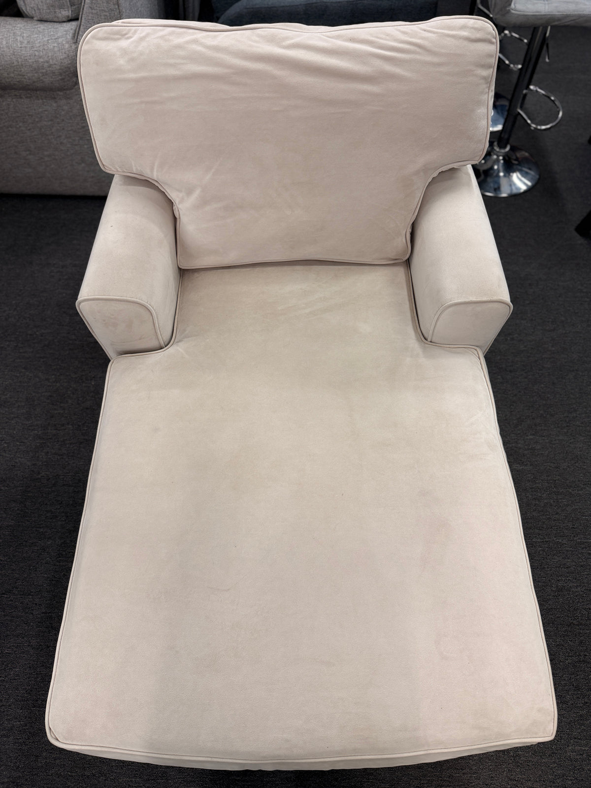 A contemporary single-seat chaise lounge upholstered in plush cream microfiber with track arms and a back cushion in good condition.