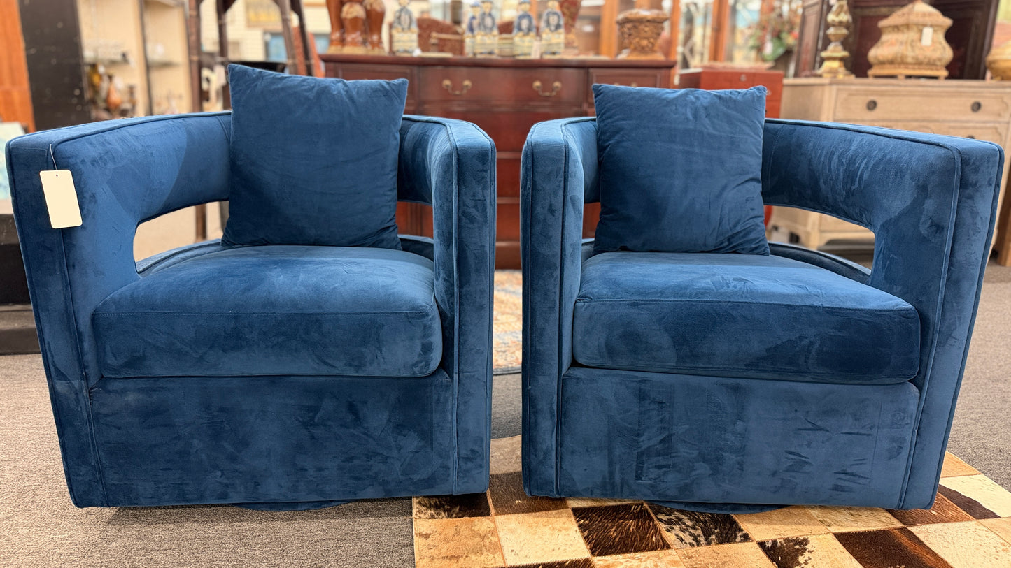 A pair of contemporary curved barrel-back swivel armchairs featuring open cutout backrests and matching square toss pillows.