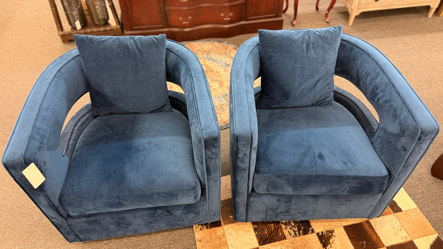 A pair of contemporary curved barrel-back swivel armchairs featuring open cutout backrests and matching square toss pillows.