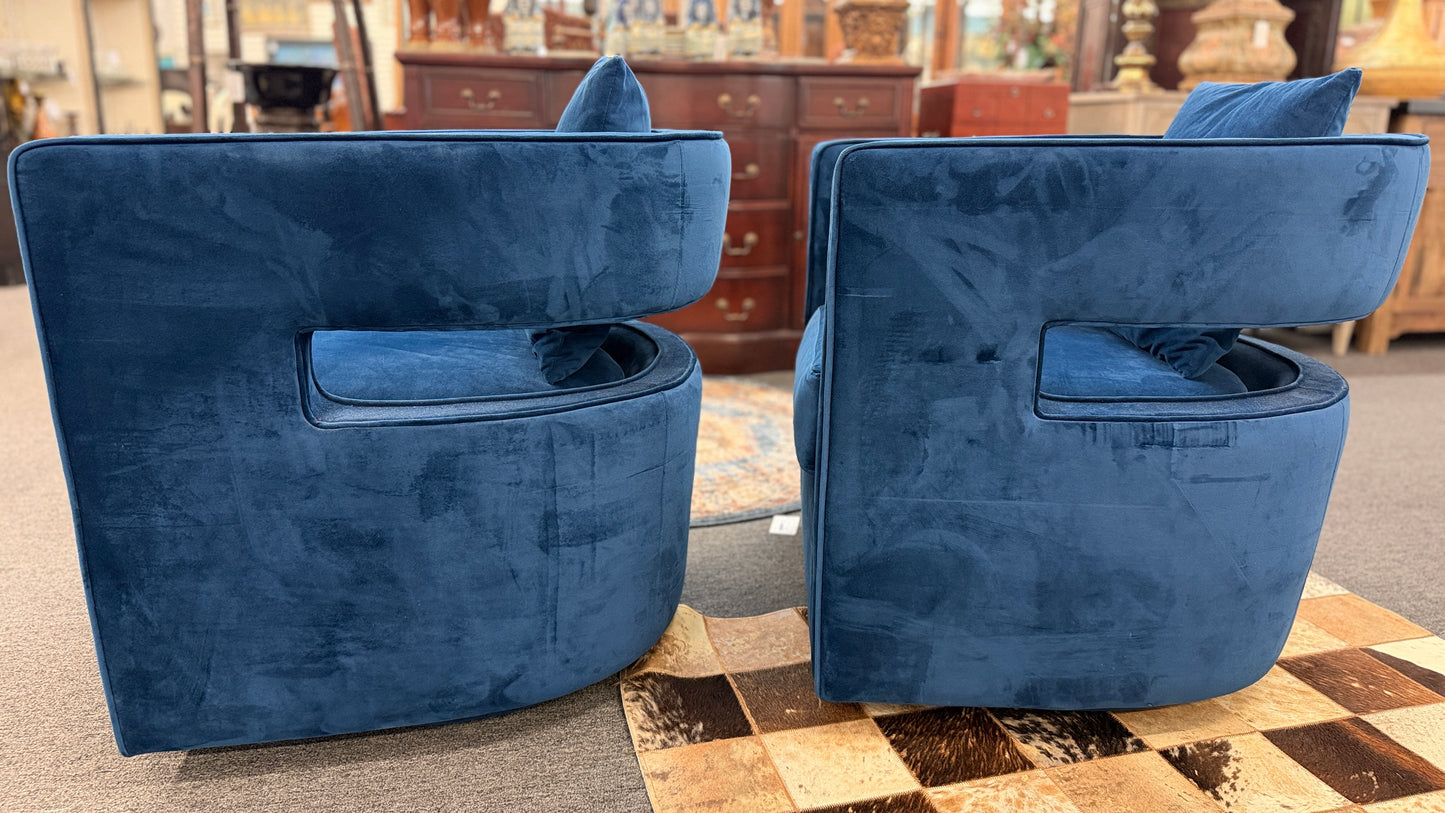 A pair of contemporary curved barrel-back swivel armchairs featuring open cutout backrests and matching square toss pillows.
