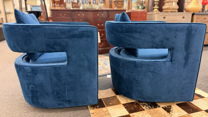 A pair of contemporary curved barrel-back swivel armchairs featuring open cutout backrests and matching square toss pillows.