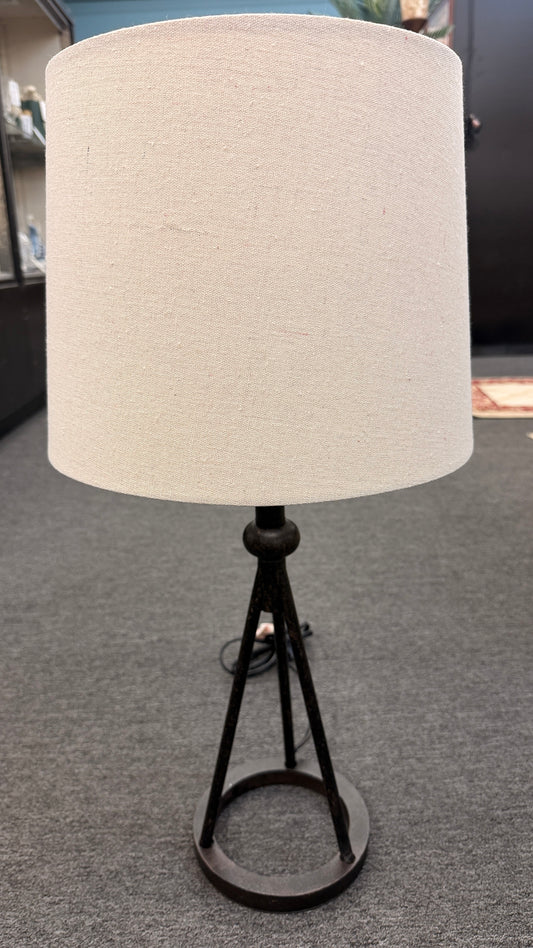 A contemporary minimalist table lamp with a dark bronze or black tripod metal base on a ring stand, topped with an oversized cylindrical off-white linen drum shade in good condition.