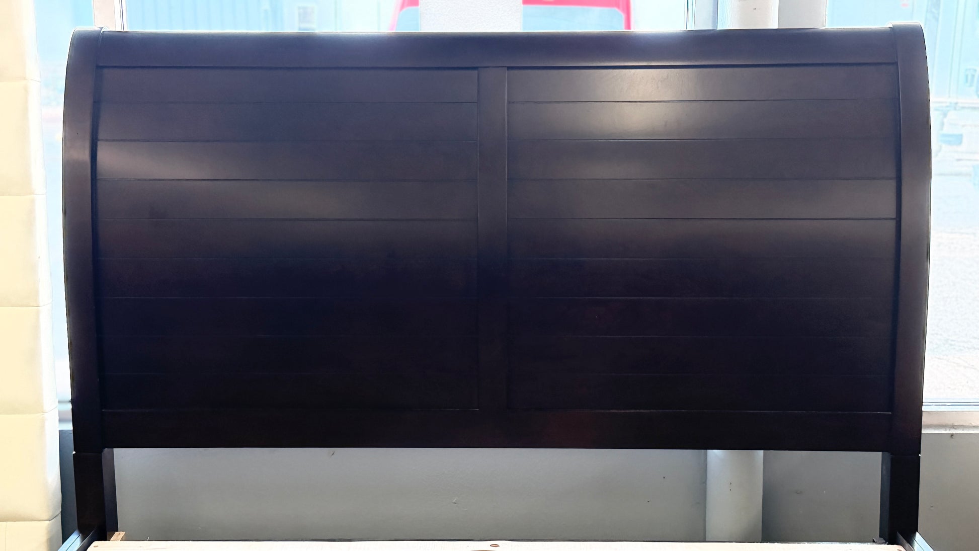 A contemporary dark-finished queen bed frame featuring a simple paneled headboard, wooden slat support, and two built-in storage drawers in the footboard.