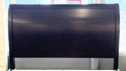 A contemporary dark-finished queen bed frame featuring a simple paneled headboard, wooden slat support, and two built-in storage drawers in the footboard.