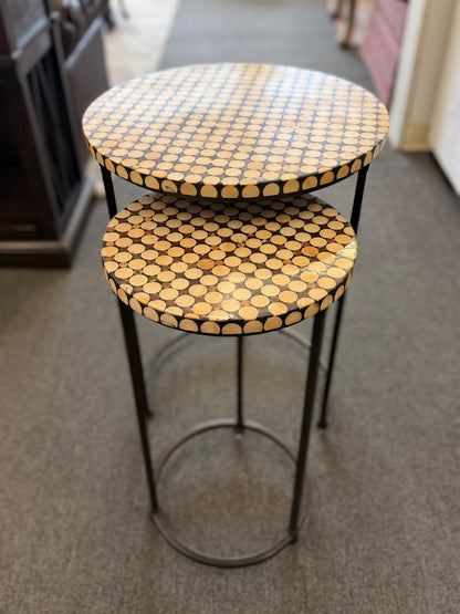 A two-piece contemporary nesting side table set featuring patterned mosaic wooden tops on slim iron tripod frames.