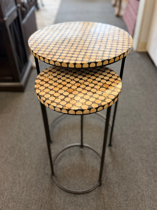 A two-piece contemporary nesting side table set featuring patterned mosaic wooden tops on slim iron tripod frames.