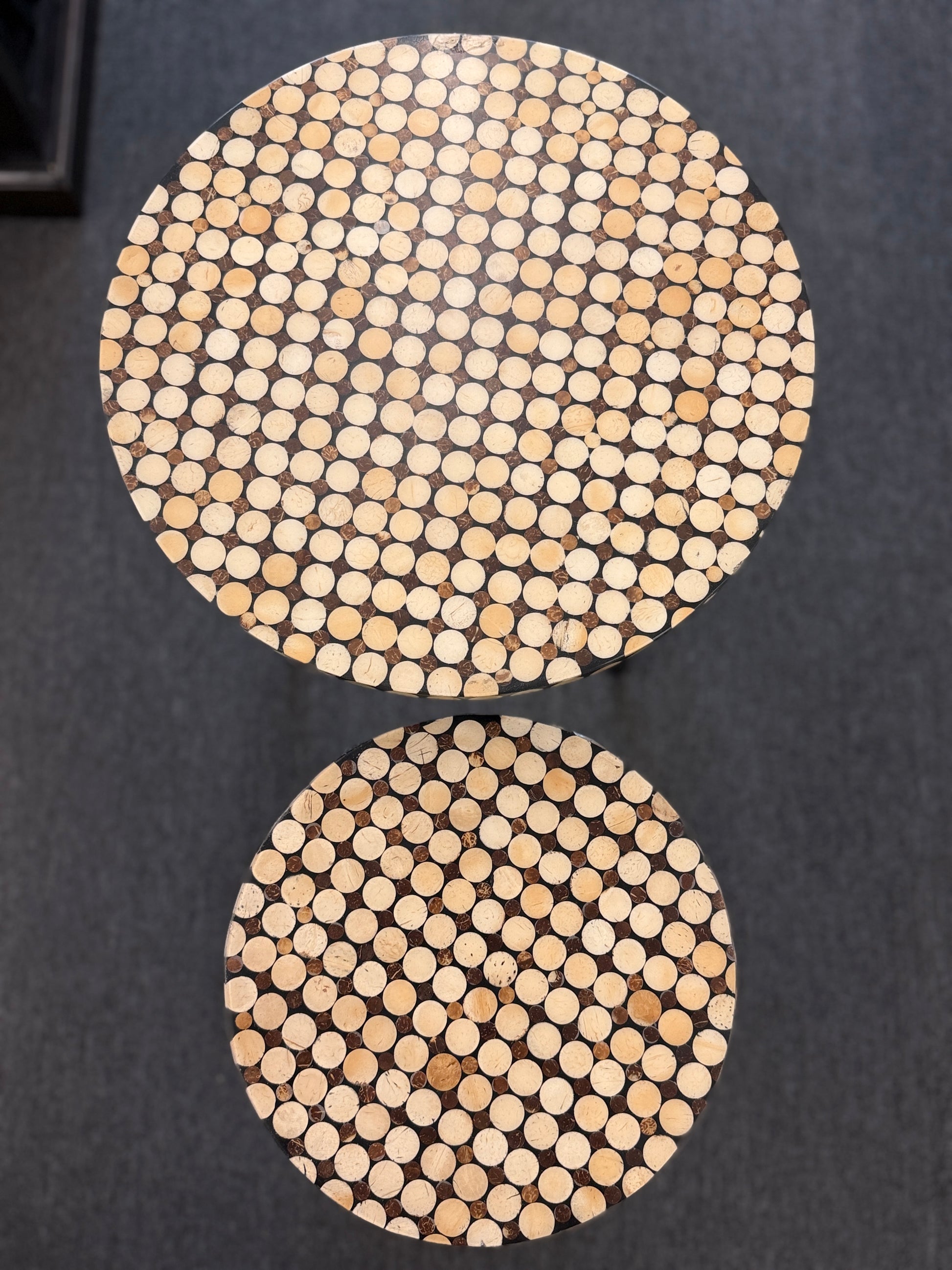 A two-piece contemporary nesting side table set featuring patterned mosaic wooden tops on slim iron tripod frames.