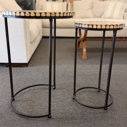 A two-piece contemporary nesting side table set featuring patterned mosaic wooden tops on slim iron tripod frames.