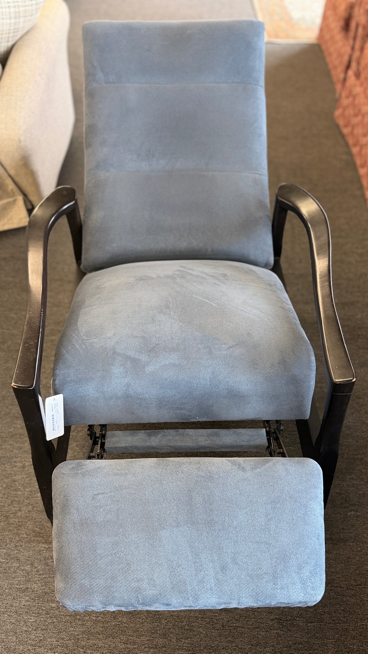A contemporary high-back recliner upholstered in slate-blue textured fabric framed by slim contoured dark-wood armrests in excellent condition.