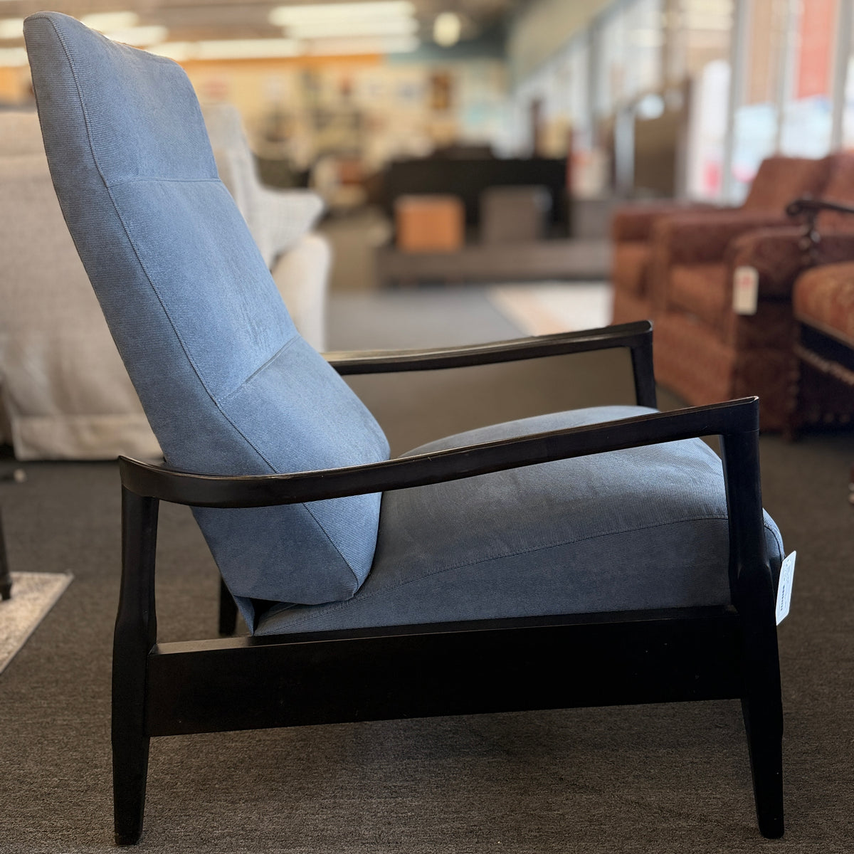 A contemporary high-back recliner upholstered in slate-blue textured fabric framed by slim contoured dark-wood armrests in excellent condition.