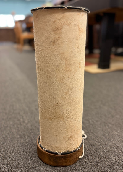 A cylindrical pergamino lamp featuring a textured parchment-style shade resting on a small dark wooden base in excellent condition.