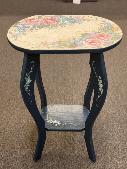 A dark blue accent table decorated with painted floral motifs on both the top surface and the lower shelf in good condition.