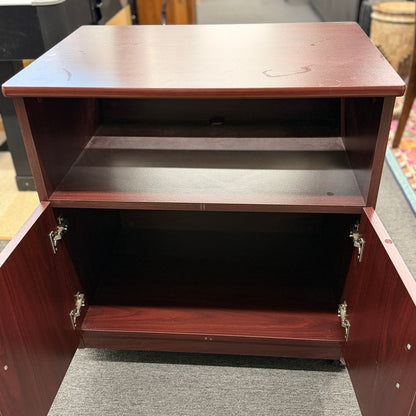 A compact mobile storage cabinet in a dark cherry finish featuring an open top shelf, double cabinet doors with curved black handles, and rolling wheels.