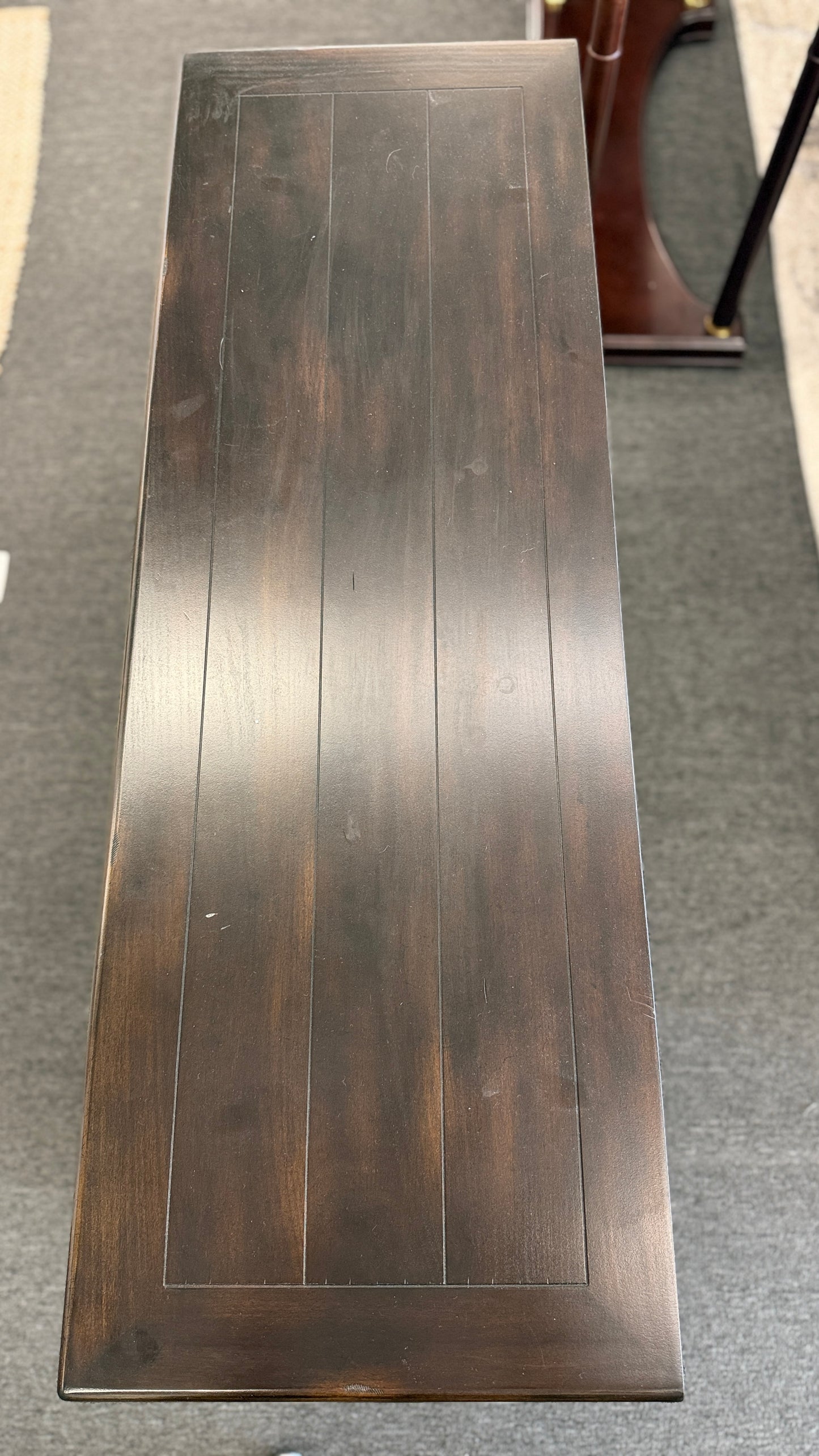 A dark-finished media console TV stand featuring X-brace side details, two small top drawers, a central open cubby with cable holes, and a large bottom shelf.