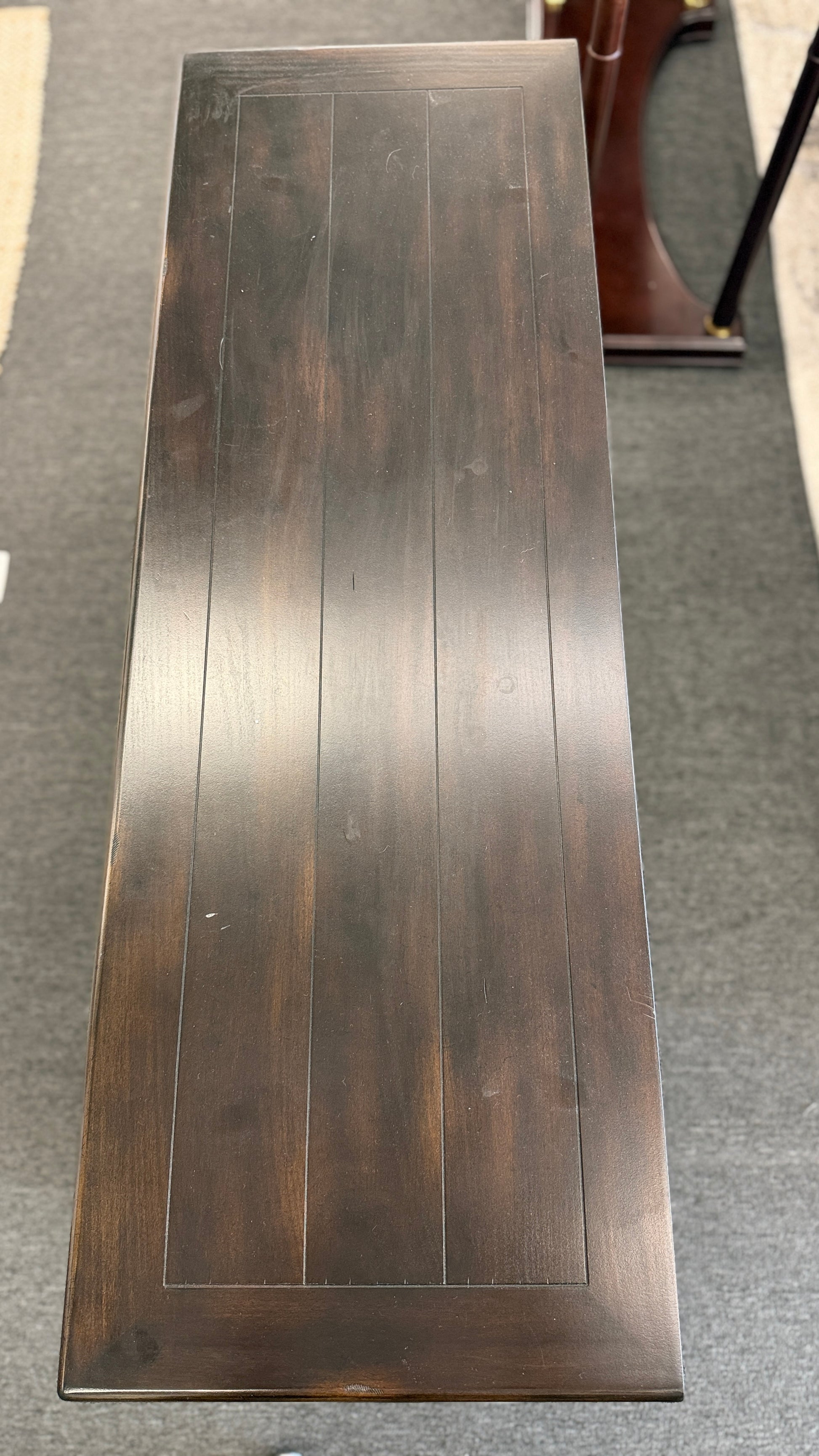 A dark-finished media console TV stand featuring X-brace side details, two small top drawers, a central open cubby with cable holes, and a large bottom shelf.