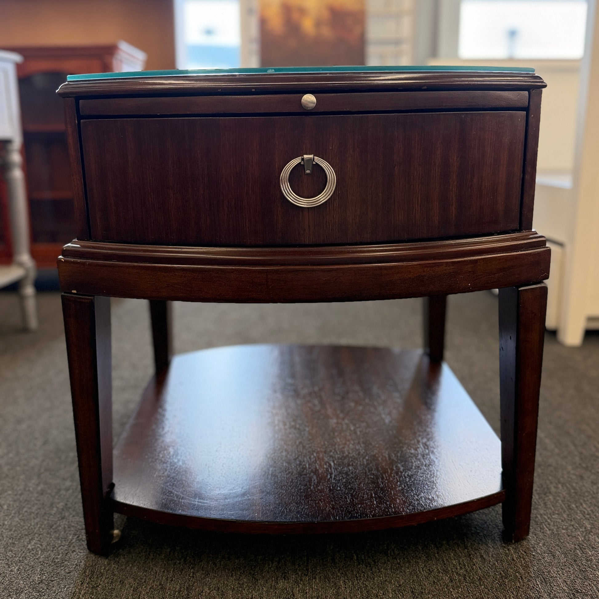 Dark wood nightstand featuring a glass insert top, a single drawer with a silver ring pull, and an open lower display shelf.