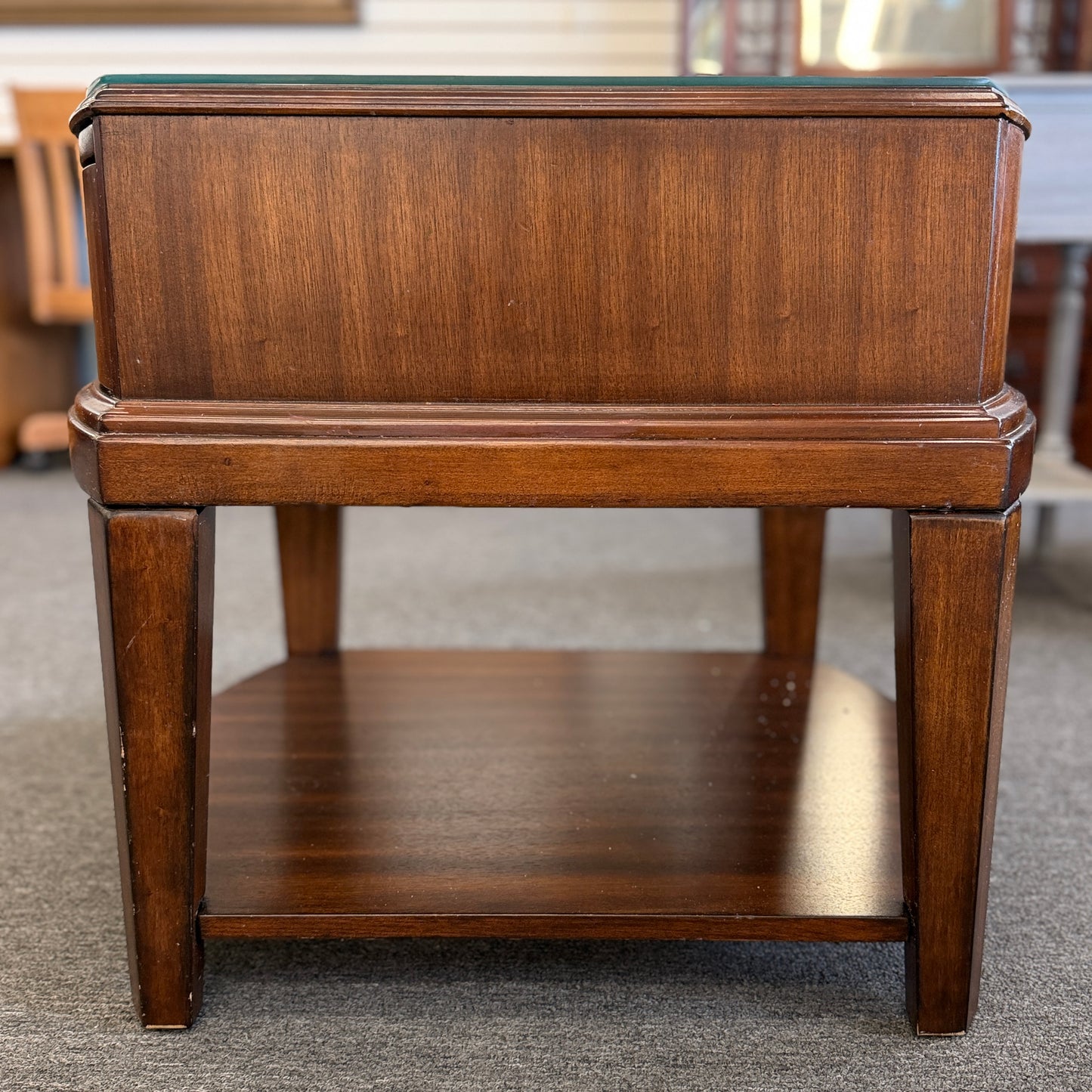 Dark wood nightstand featuring a glass insert top, a single drawer with a silver ring pull, and an open lower display shelf.