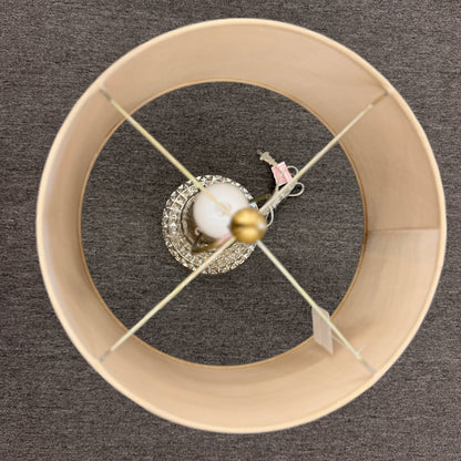 A modern transitional accent lamp featuring a diamond-quilted tinted glass urn base on a brass platform with a beige linen drum shade.