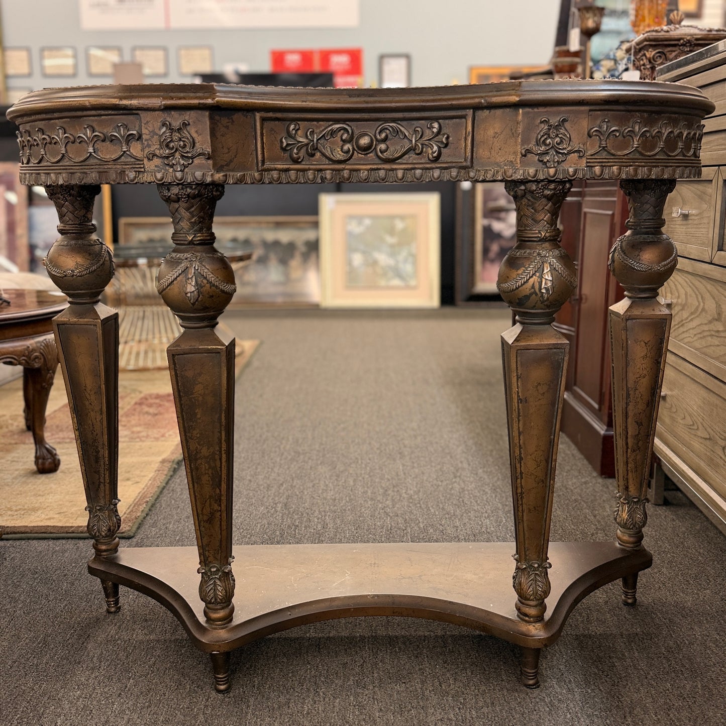 Distressed wood console table featuring ornate carved details, a center drawer, sculpted legs, and a gracefully curved lower stretcher.