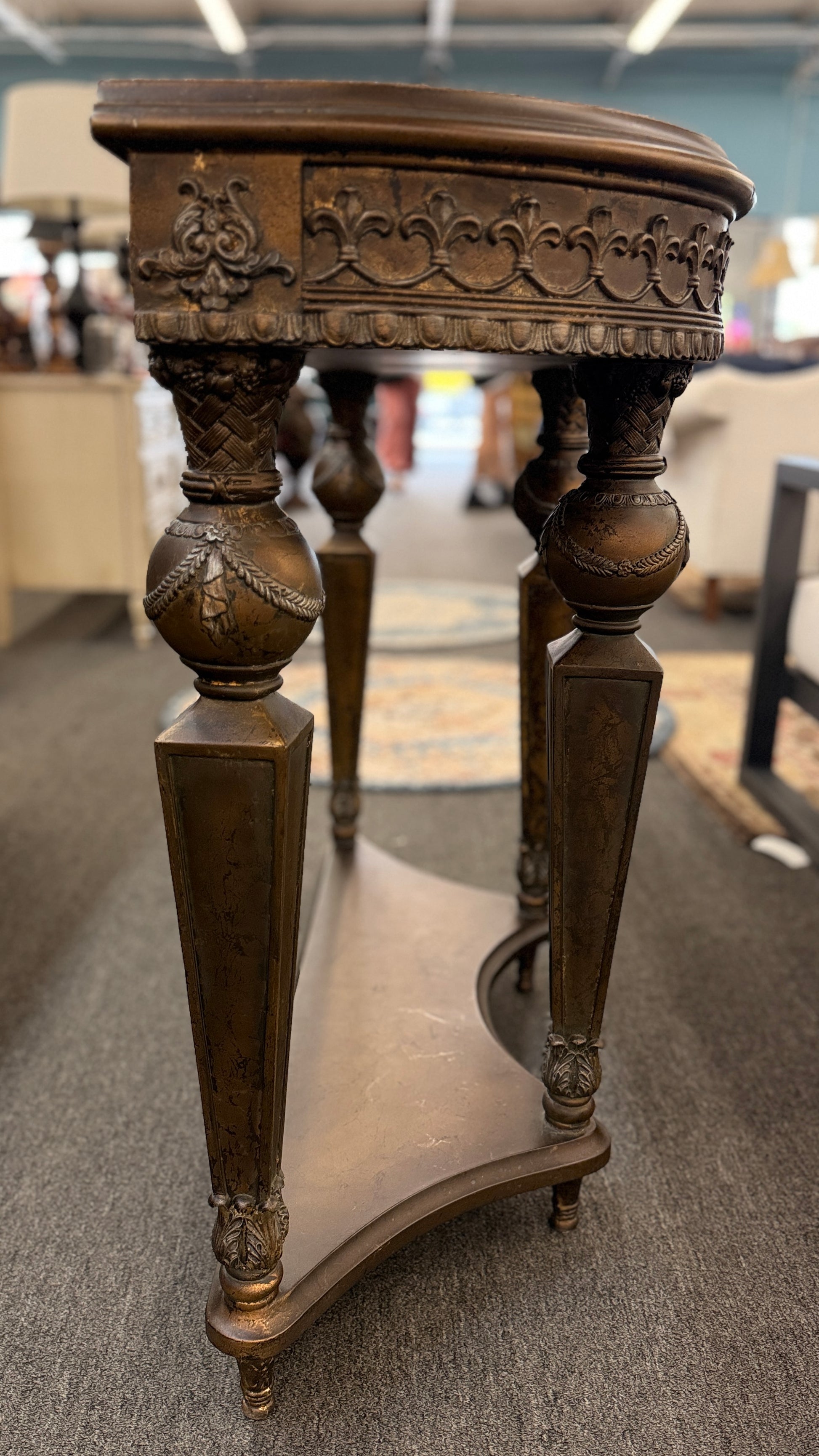 Distressed wood console table featuring ornate carved details, a center drawer, sculpted legs, and a gracefully curved lower stretcher.