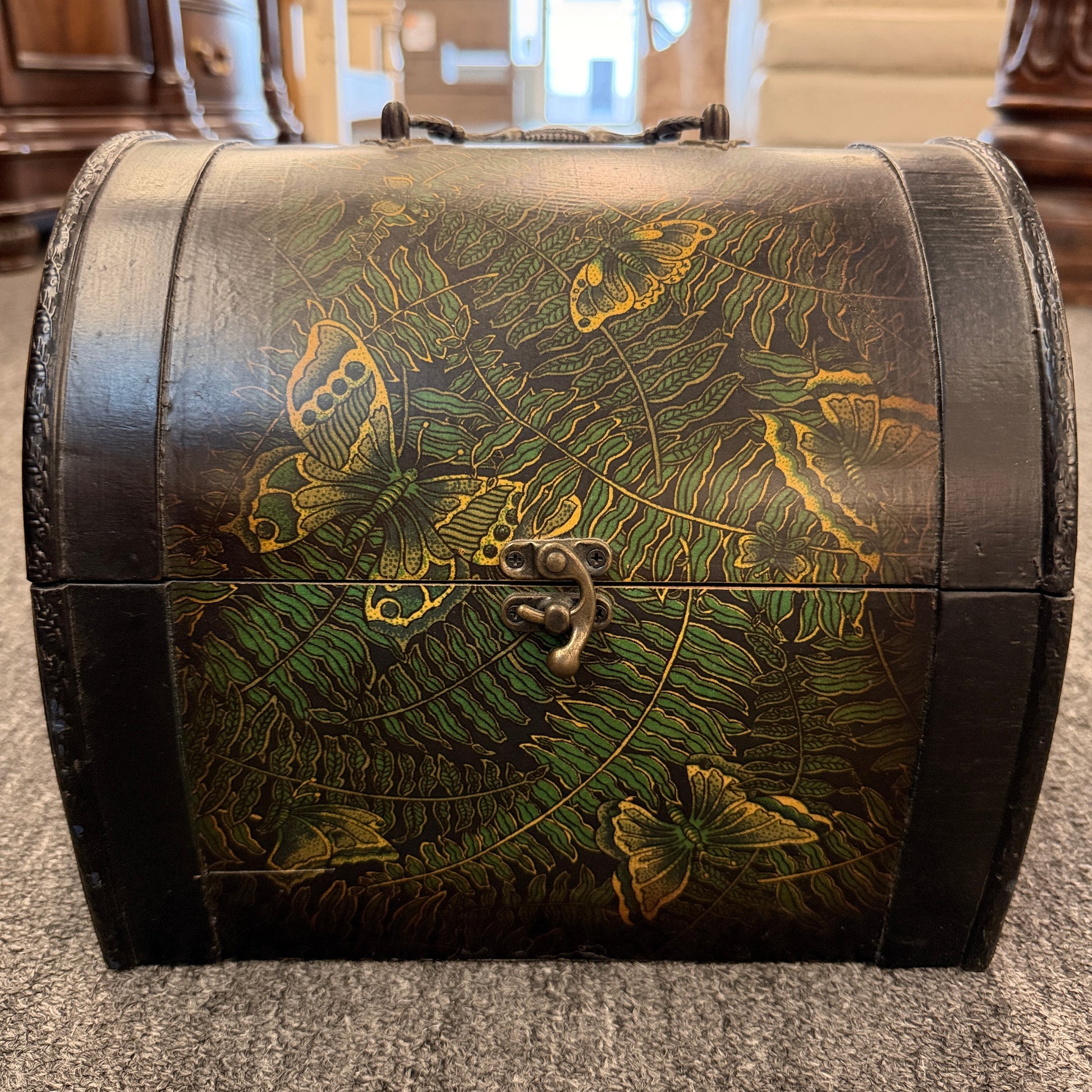 A small domed-top wooden treasure chest featuring green fern patterns, gold butterfly motifs, a metal swing clasp, and top handle in good condition.