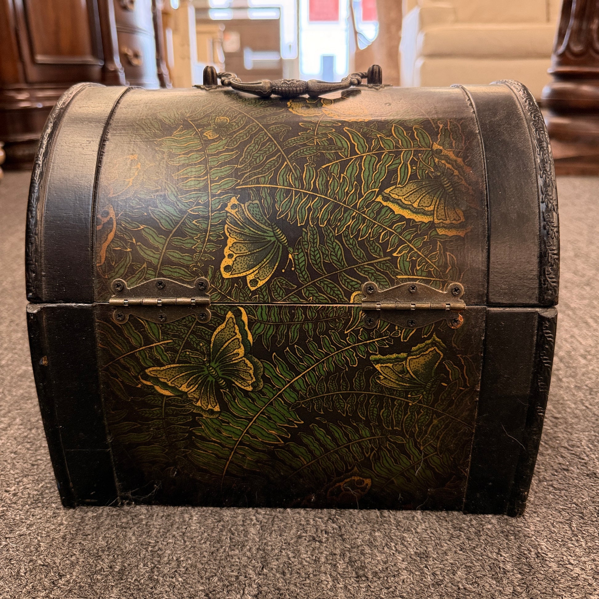 A small domed-top wooden treasure chest featuring green fern patterns, gold butterfly motifs, a metal swing clasp, and top handle in good condition.