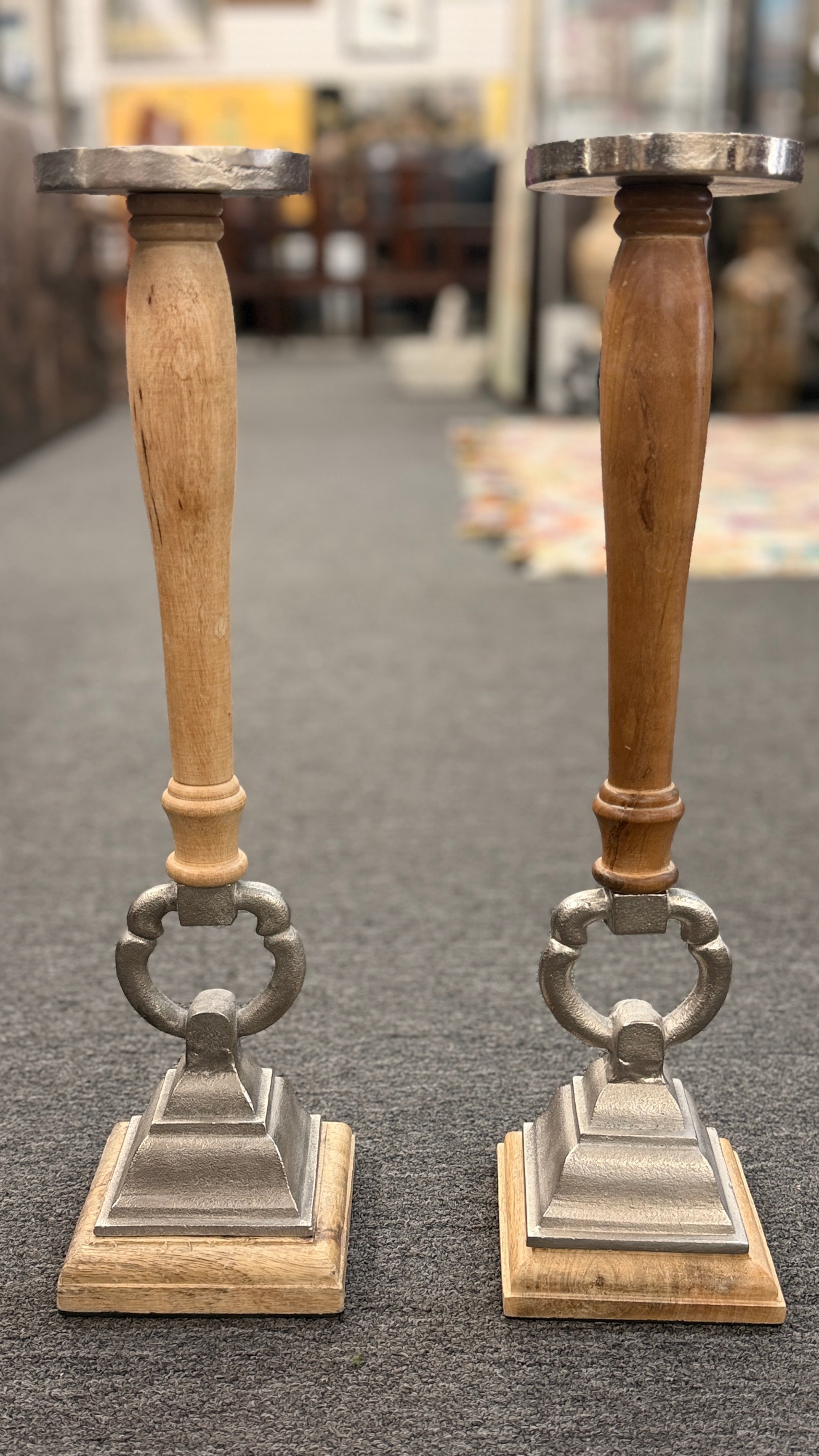 A pair of tall, eclectic pillar candle holders featuring turned wooden spindles, cast-metal open-ring accents, and tiered square plinth bases.