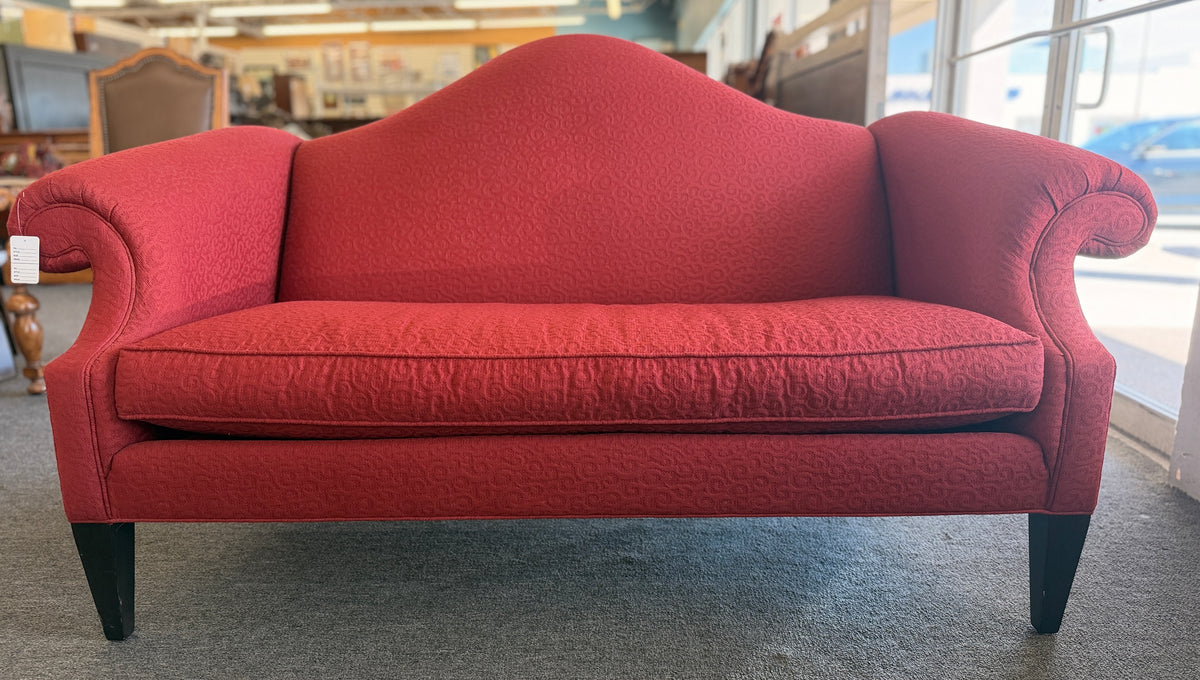 A bright red upholstered Ethan Allen loveseat with a subtly patterned fabric, curved backrest, and dark tapered legs in good condition.