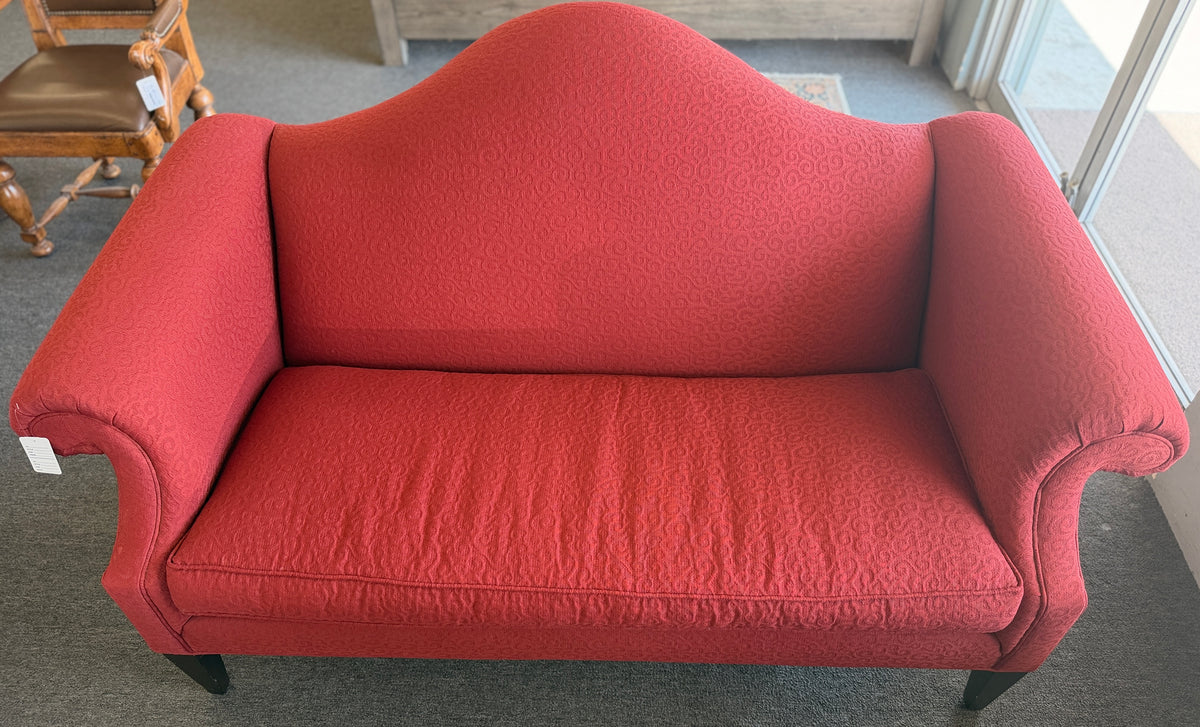 A bright red upholstered Ethan Allen loveseat with a subtly patterned fabric, curved backrest, and dark tapered legs in good condition.