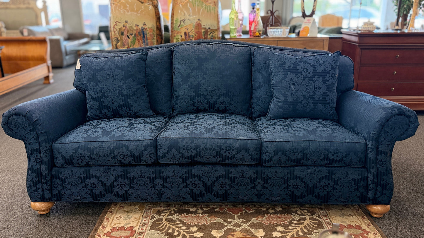 Traditional Ethan Allen three-seater sofa upholstered in blue tone-on-tone damask fabric with English rolled arms, three seat cushions, three back cushions, two matching accent pillows, and turned wooden bun feet.