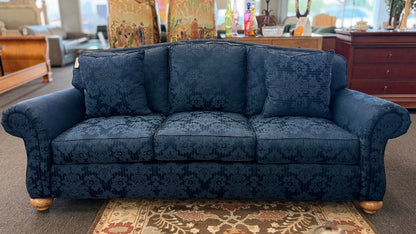 Traditional Ethan Allen three-seater sofa upholstered in blue tone-on-tone damask fabric with English rolled arms, three seat cushions, three back cushions, two matching accent pillows, and turned wooden bun feet.
