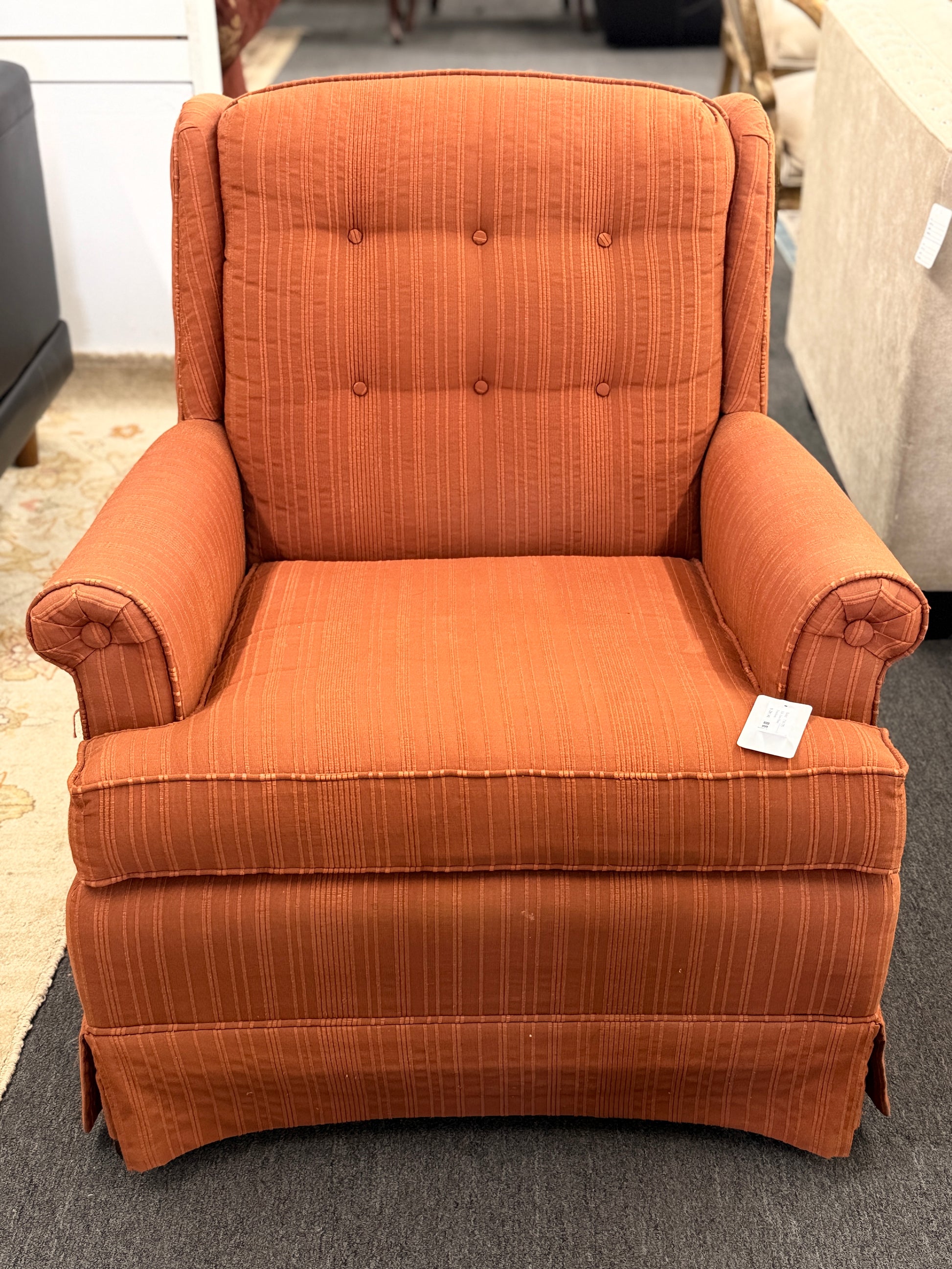 Ethan Allen upholstered armchair featuring rust-orange striped fabric, a button-tufted backrest, padded rolled arms, and a tailored skirted base.