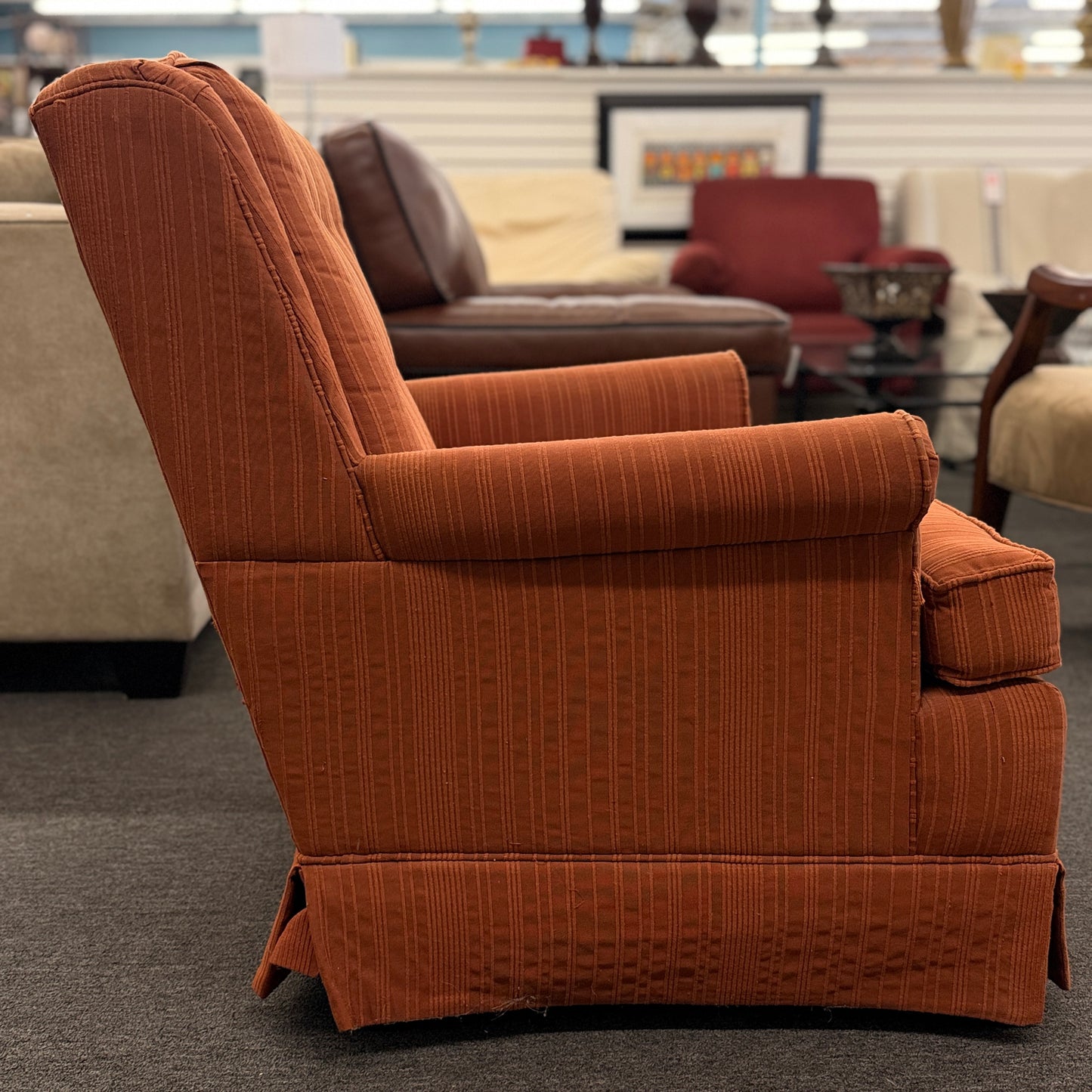 Ethan Allen upholstered armchair featuring rust-orange striped fabric, a button-tufted backrest, padded rolled arms, and a tailored skirted base.