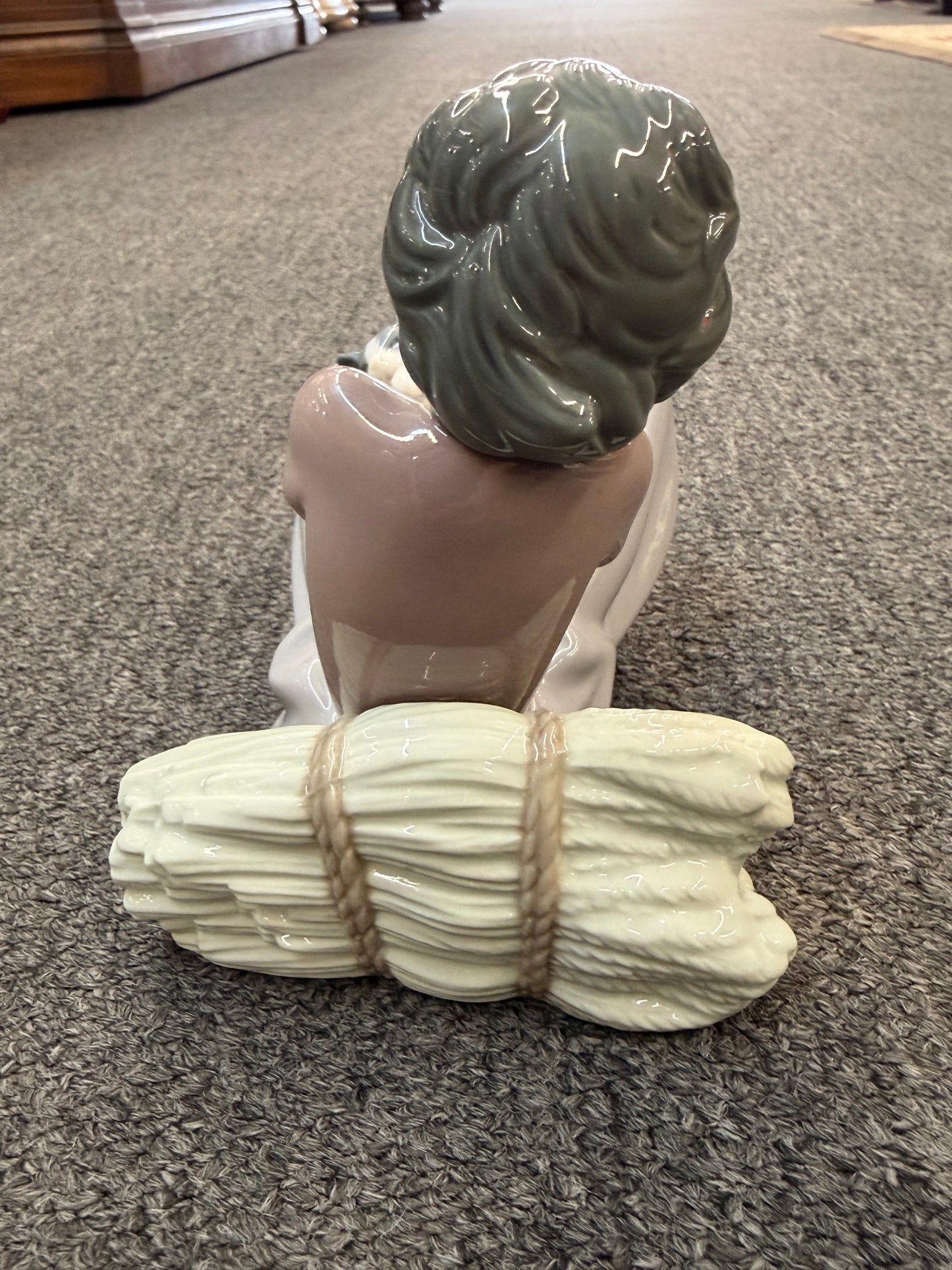 A fine porcelain figurine depicting a seated girl in a lavender-grey dress playing with a grey and white cat beside a sheaf of wheat in excellent condition.