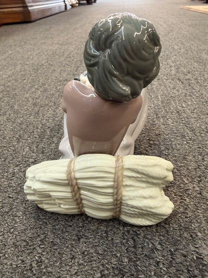 A fine porcelain figurine depicting a seated girl in a lavender-grey dress playing with a grey and white cat beside a sheaf of wheat in excellent condition.