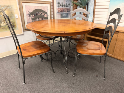 Five-piece round dining set featuring a natural wood tabletop, four matching chairs with wood seats, and decorative curved metal frames with scrollwork.