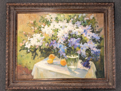A heavy-impasto floral painting featuring white and periwinkle flowers in a glass vase with citrus fruit in an ornate bronze frame in excellent condition.