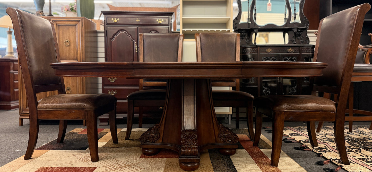 A formal 7-piece dining set featuring an oval dark wood extension table with a carved pedestal base and six upholstered high-back chairs with rolled silhouettes.