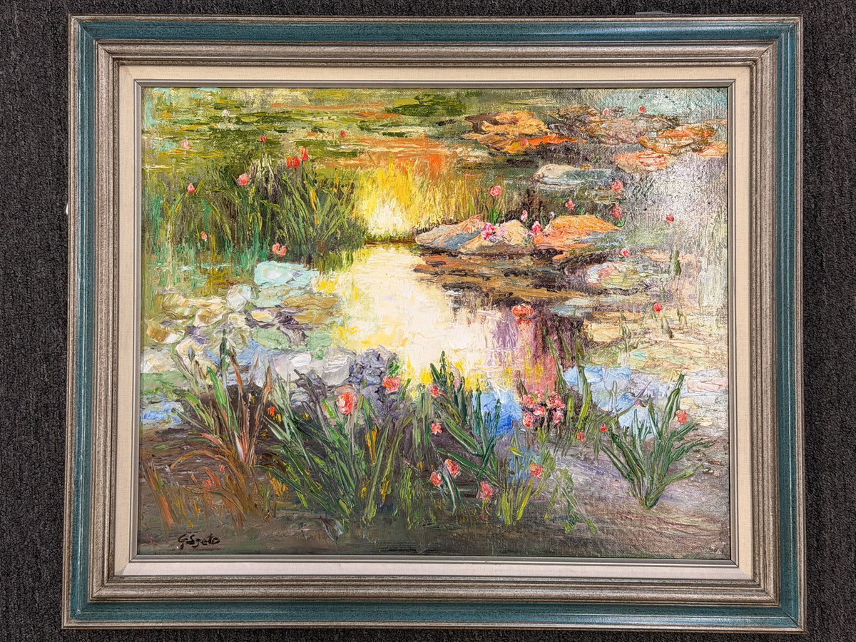 A framed Impressionist-style oil painting depicting a sunlit water lily pond, encased in a molded gray-blue and silver frame in excellent condition.