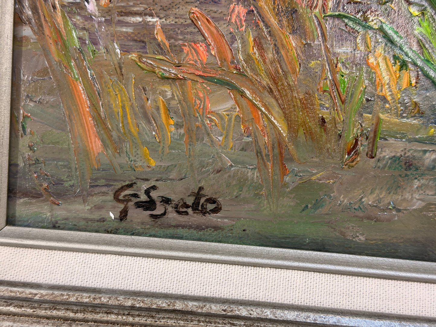 A framed Impressionist-style oil painting depicting a sunlit water lily pond, encased in a molded gray-blue and silver frame in excellent condition.