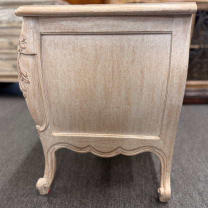 A French Provincial style two-drawer nightstand in a distressed antique-white finish featuring a serpentine front, cabriole legs, and ornate iron pulls.