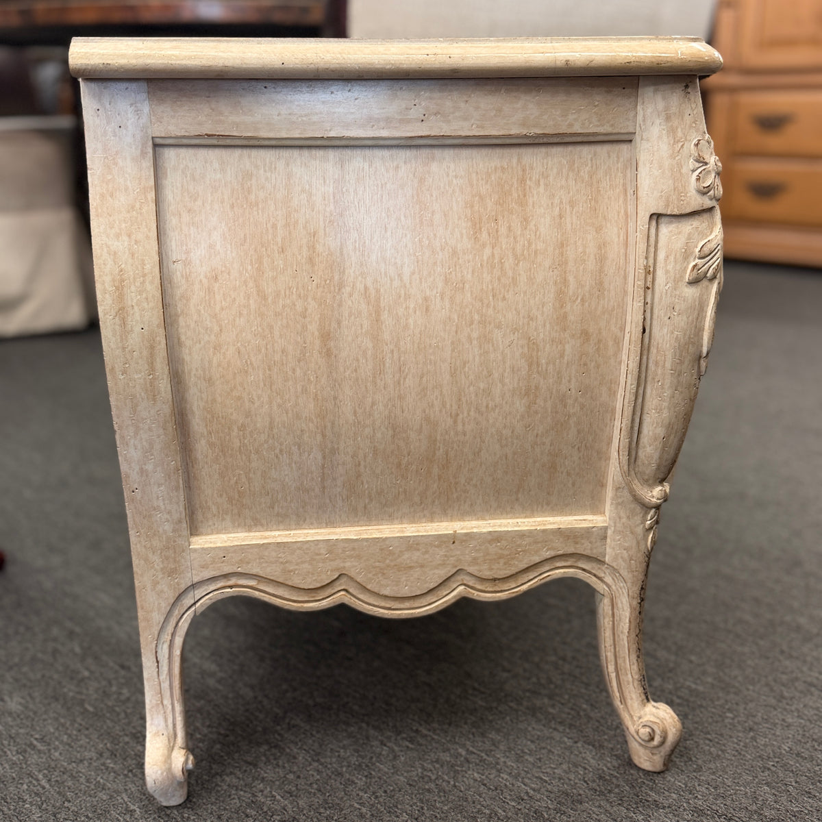 A French Provincial style two-drawer nightstand in a distressed antique-white finish featuring a serpentine front, cabriole legs, and ornate iron pulls.