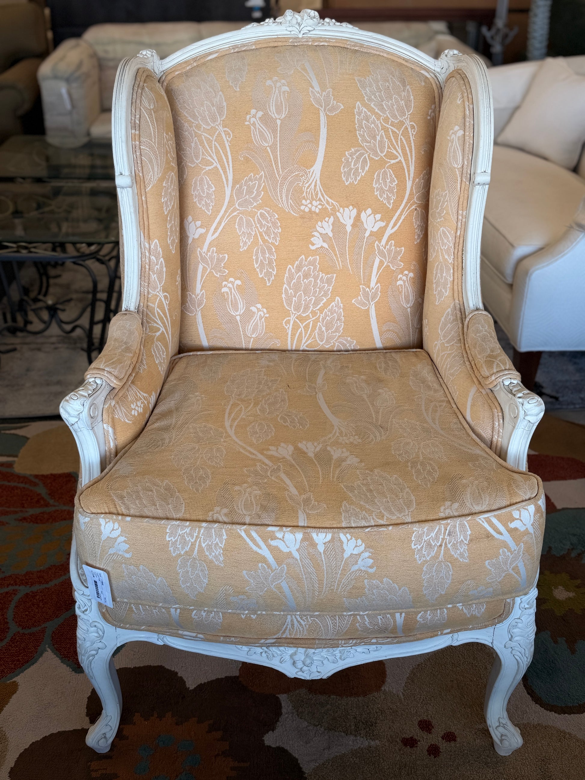 An elegant French provincial-style wingback armchair with an ornate carved white wood frame, tufted-style high backrest, loose seat cushion, and curved cabriole legs.